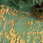 Detaliu macro al traversei din plasa aratand aplicatiile neregulate de foita aurie pe un fundal verde.