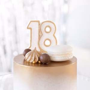 Lumânare Majorat Numărul 18 Aurie Cu Sclipici Lumânare Aniversară Aurie Cu Numărul 18, Conturată Cu Sclipici, Așezată Pe Un Tort Elegant Decorat Cu Auriu, Bezele Și Un Macaron Alb.