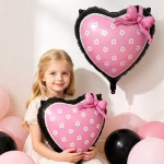 Prim plan cu o fetita care imbratiseaza balonul folie inima evidentiind contrastul dintre centrul roz cu flori si marginea neagra