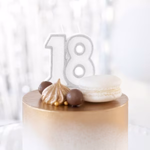Lumânare Majorat Numărul 18 Argintie Cu Sclipici Lumânare Aniversară Argintie Cu Numărul 18, Conturată Cu Sclipici, Așezată Pe Un Tort Elegant Decorat Cu Nuanțe De Auriu, Bezele Și Un Macaron.