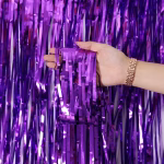 Perdea decorativa din franjuri tip tinsel realizata din folie metalizata de culoare mov intens tinuta in mana pentru a evidentia textura lucioasa