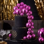 Tort etajat negru decorat cu o cascada spectaculoasa de sfere roz fucsia cu efect de glob disco de diferite dimensiuni alaturi de sclipici auriu