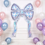 Balon gigant din folie în formă de fundiță cu panglici lungi, având un finisaj iridiscent care reflectă nuanțe holografice pastelate, fixat pe un perete elegant de culoare albă