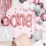 Balon din folie metalizata de culoare auriu-roz modelat elegant sub forma literelor cursive legate care formeaza cuvantul englezesc one