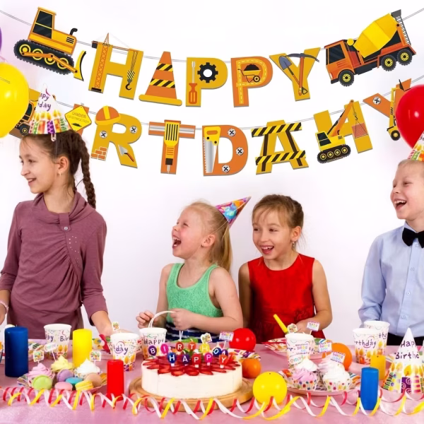 Banner festiv cu mesajul Happy Birthday, suspendat deasupra unei mese de petrecere pentru copii, având literele decorate creativ cu motive de șantier, utilaje, dungi de avertizare și unelte