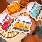 Set de 6 farfurii din carton decupate in forma de locomotiva de tren cu aburi in trei culori asortate menta galben si rosu cu inscriptia Happy Express