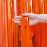 Perdea din franjuri tip tinsel realizata din folie lucioasa de culoare portocaliu intens cu suvite verticale fine tinute in mana pentru a evidentia textura materialului