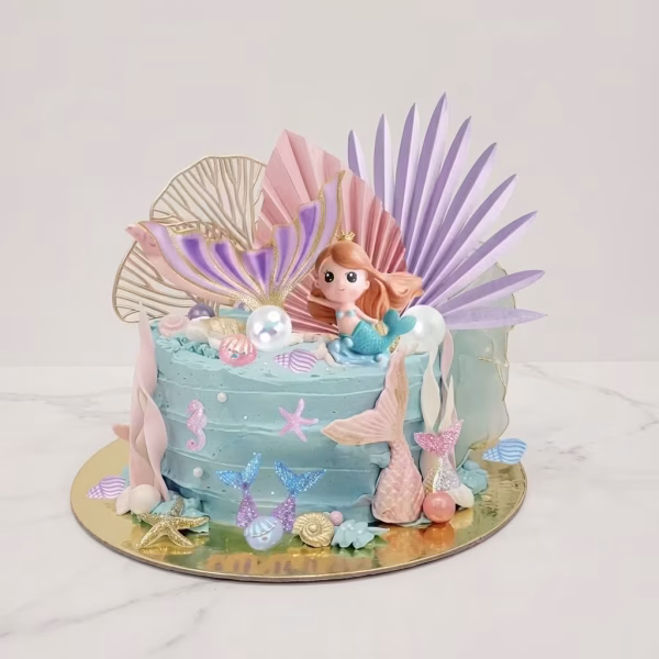 Tort decorat cu tematica marina incluzand o figurina sirena 3D, cozi de sirena, perle, scoici, frunze evantai pastelate si elemente aurii