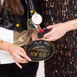 Set de 6 toppere rotunde din carton pentru tort de Revelion, ilustrând fețe de ceas care indică apropierea miezului nopții, dintre care trei au fundal alb cu contur auriu și trei au fundal negru cu detalii aurii