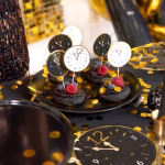 Set de 6 toppere rotunde din carton pentru tort de Revelion, ilustrând fețe de ceas care indică apropierea miezului nopții, dintre care trei au fundal alb cu contur auriu și trei au fundal negru cu detalii aurii