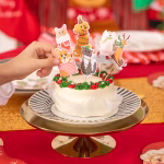 Set de 6 toppere din carton pentru tort, ilustrând animăluțe simpatice în ipostaze amuzante de iarnă: un urs polar patinând, o pisică morocănoasă și un cățel încurcați în luminițe de Crăciun, un ren pe sanie, o pisicuță într-o șosetă festivă și un corgi ieșind dintr-un cadou