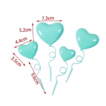 Set de 4 toppere din plastic lucios in forma de inimi tip balon de culoare turcoaz, prevazute cu tije ondulate ce imita panglicile, asezate ca decor pe un tort asortat in aceeasi nuanta