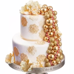 Tort etajat alb decorat cu o cascada eleganta formata din sfere de polistiren auriu lucios si auriu cu sclipici, alaturi de flori delicate in culori deschise si motive decorative tip mandala aplicate pe blat