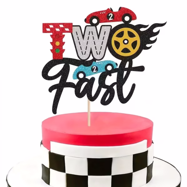 Tort decorat cu un topper din carton cu sclipici ce afiseaza mesajul Two Fast, incluzand masini de curse, un semafor in loc de litera T si o roata in flacari in loc de litera O
