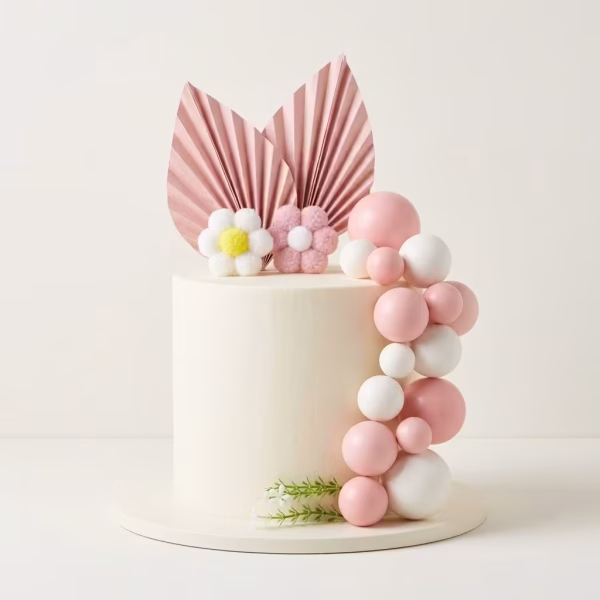 Tort decorat elegant cu un set de toppere format din frunze evantai roz din hartie, flori din material textil moale si un aranjament in cascada din sfere albe si roz
