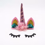 Tort alb decorat cu un topper unicorn 3D avand corn roz metalizat si urechi cu sclipici auriu, alaturi de ochi din carton negru aplicati pe glazura frontala
