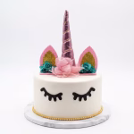 Tort alb decorat cu un topper unicorn 3D avand corn roz metalizat si urechi cu sclipici auriu, alaturi de ochi din carton negru aplicati pe glazura frontala